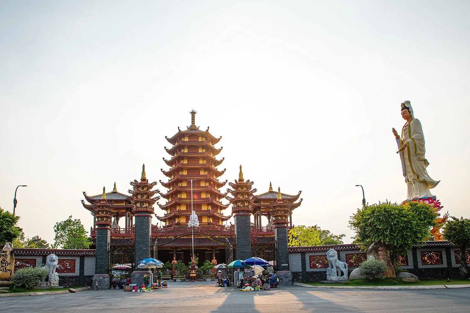 Cổng chùa, bảo tháp và tượng Phật giữa khuôn viên cây xanh